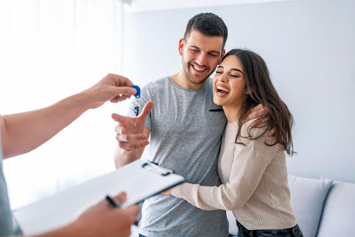 smiling man and woman grabbing keys from man with clipboard